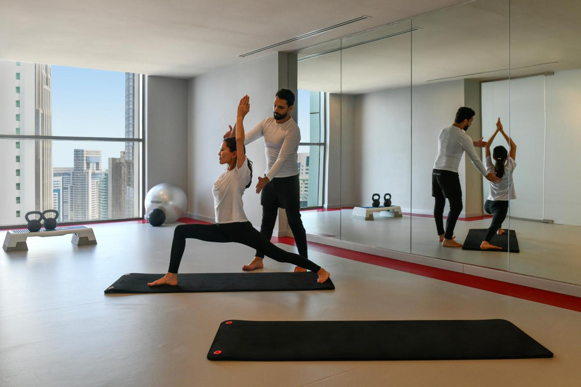 Dusit Doha Hotel מראה חיצוני תמונה A personal trainer assisting a woman with a yoga workout